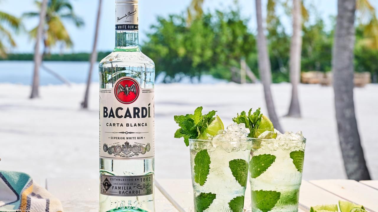 bottle of bacardi rum and cocktails with a beach in the background