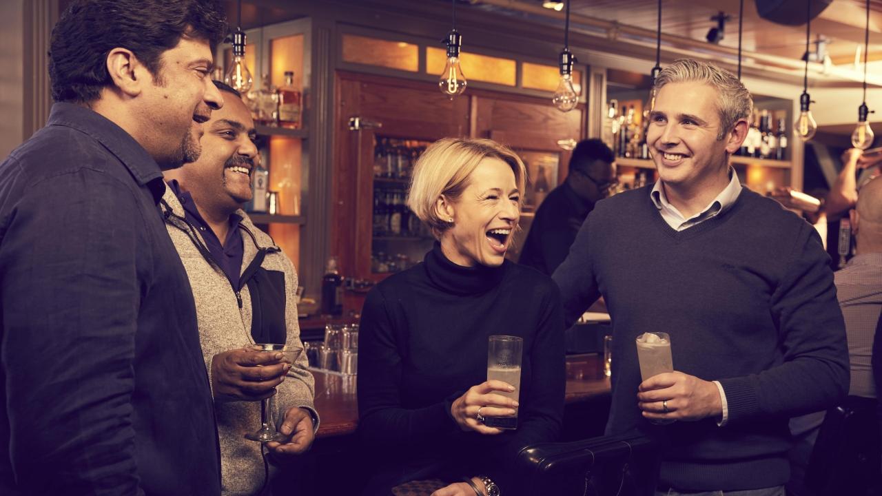 4 people enjoy drinks at a bar
