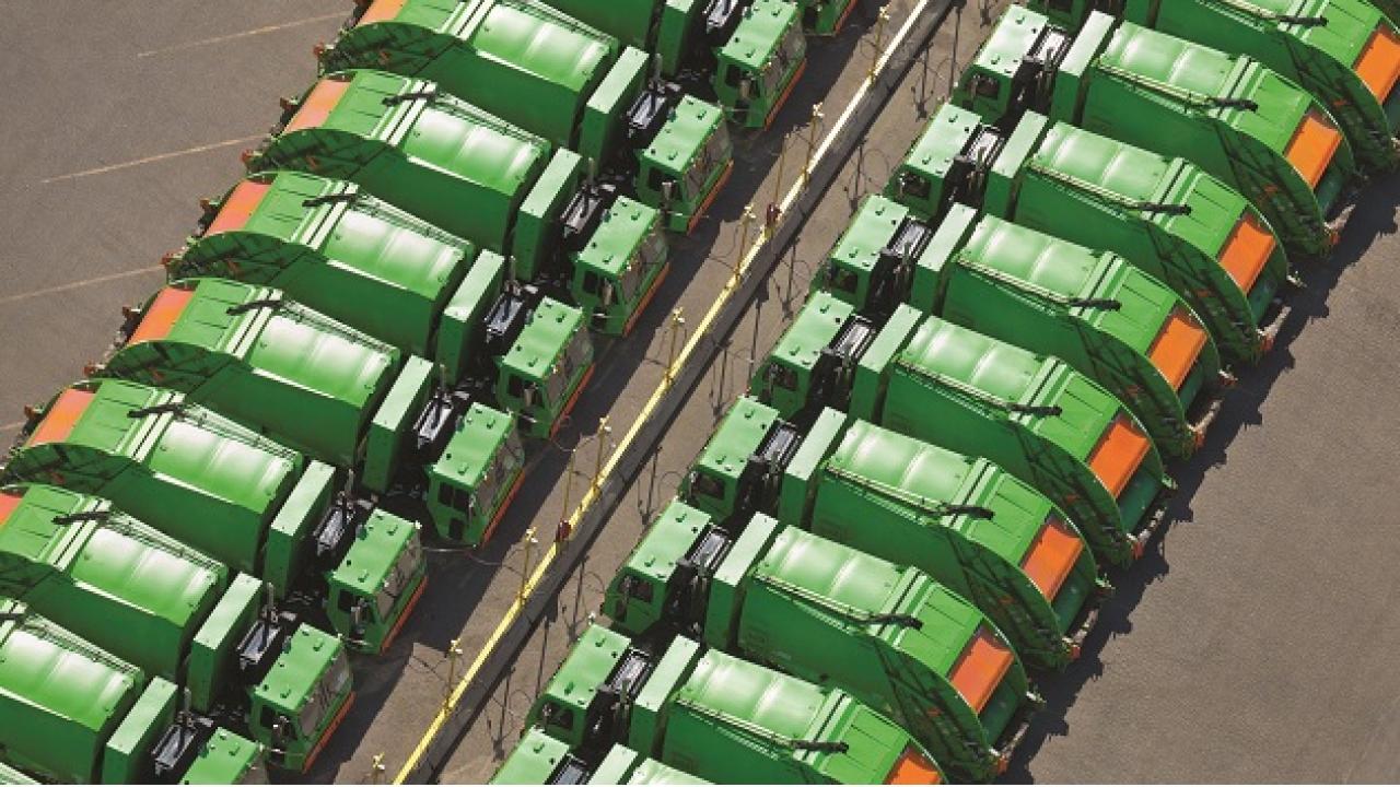aerial view of two rows of green garbage trucks