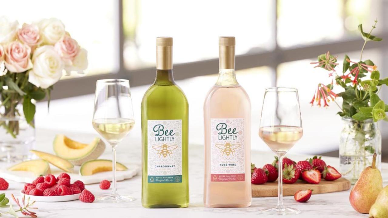 Two bottles of "Bee Lightly" wines with wine glasses and fruit on table