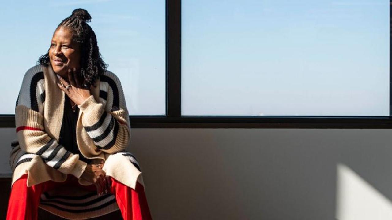 Benita Harrington sat on a bench in front of a window 