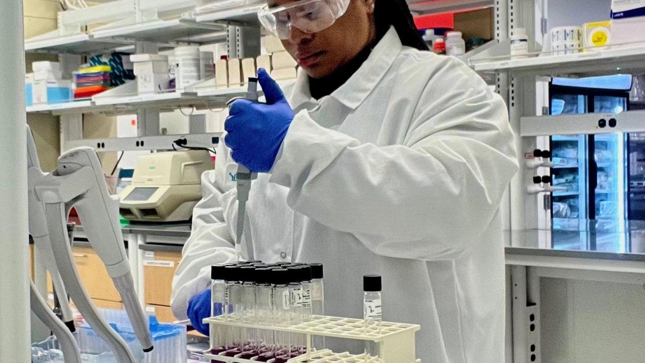 Scientist Bernice Karlton-Senaye, Ph.D. adds liquid to test tubes in a laboratory