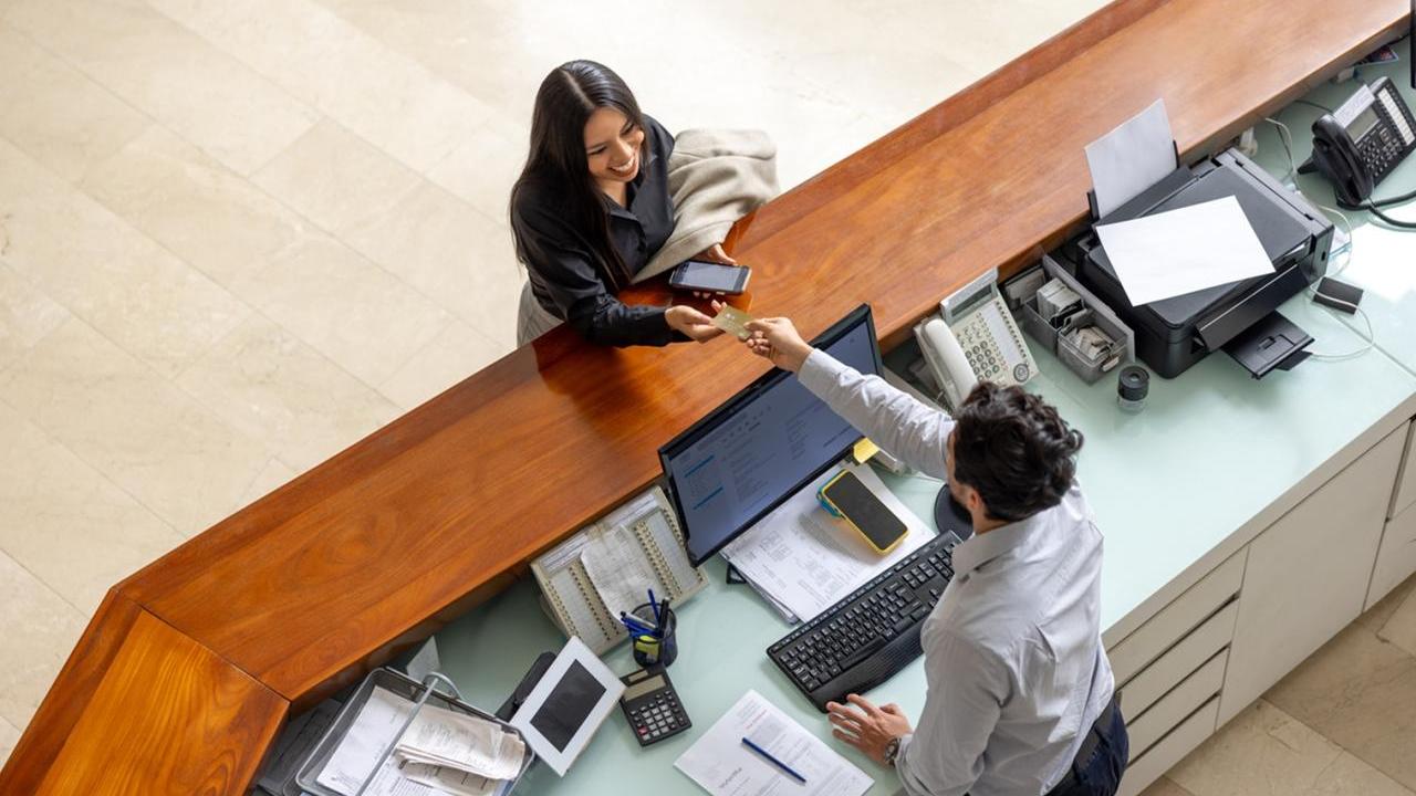 Aerial view of woman paying for hotel stay at front desk