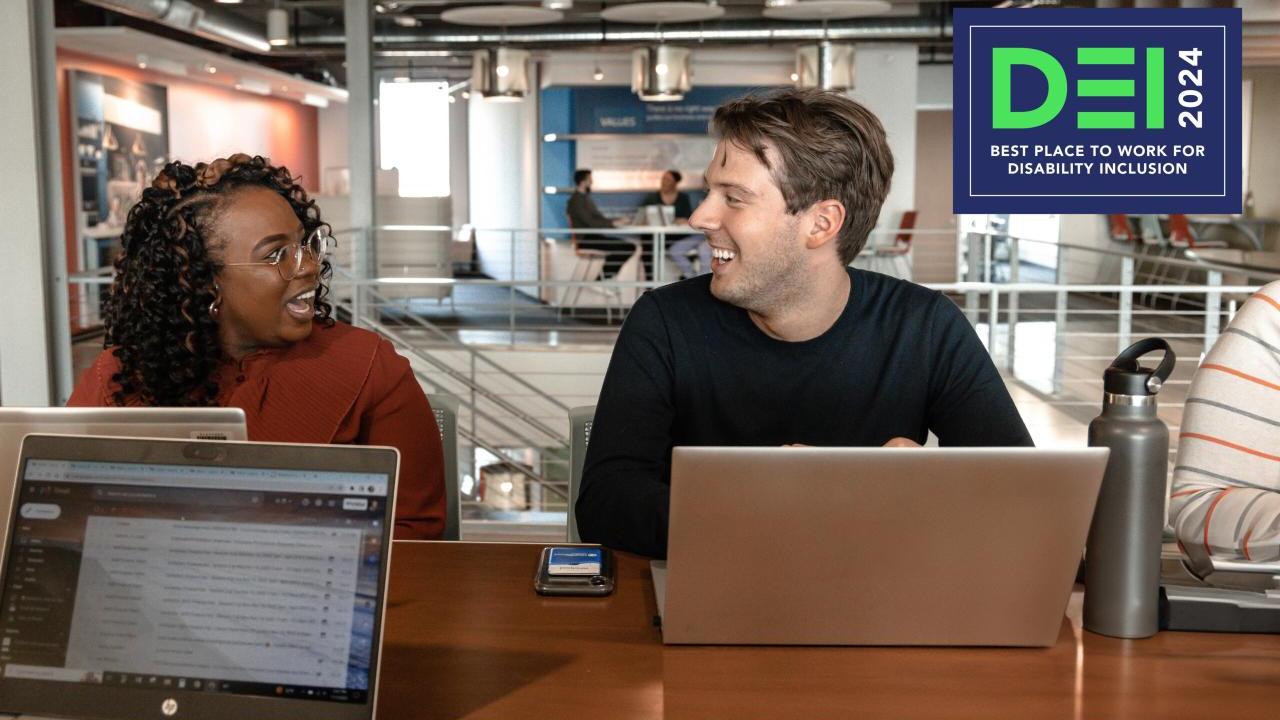 Two people using laptops and talking