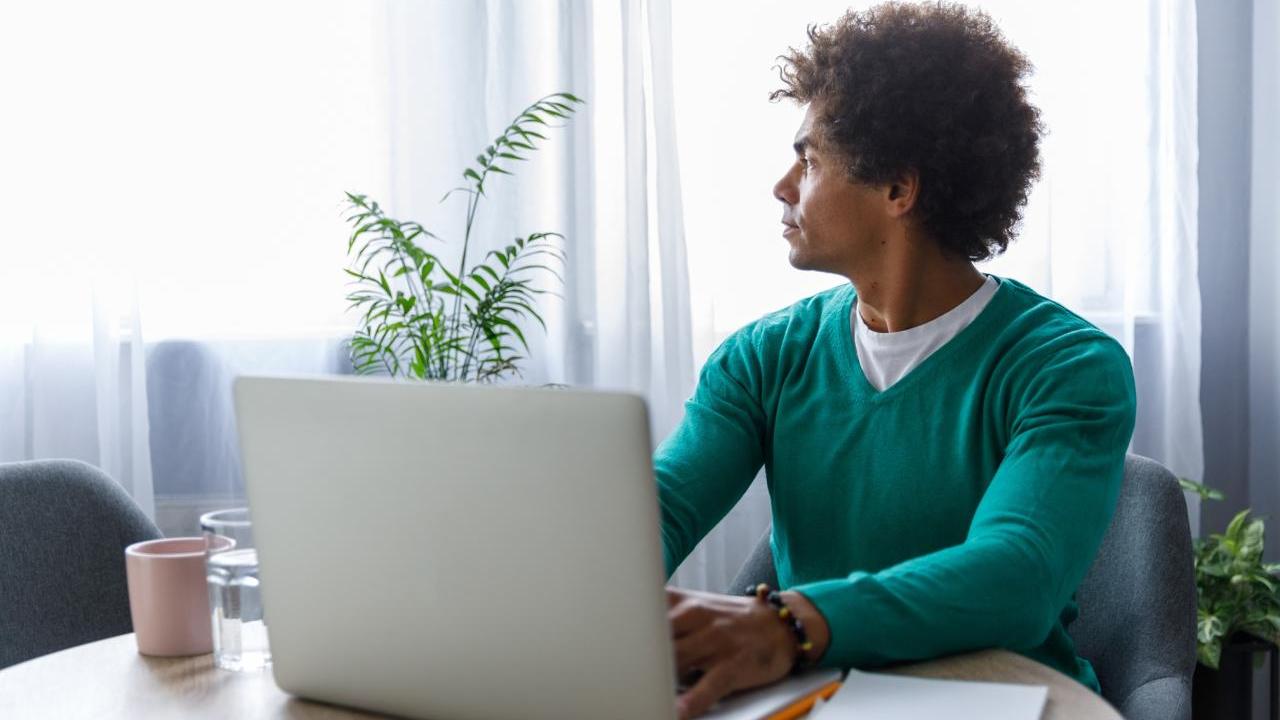 Man sitting at a desk looking towards a window
