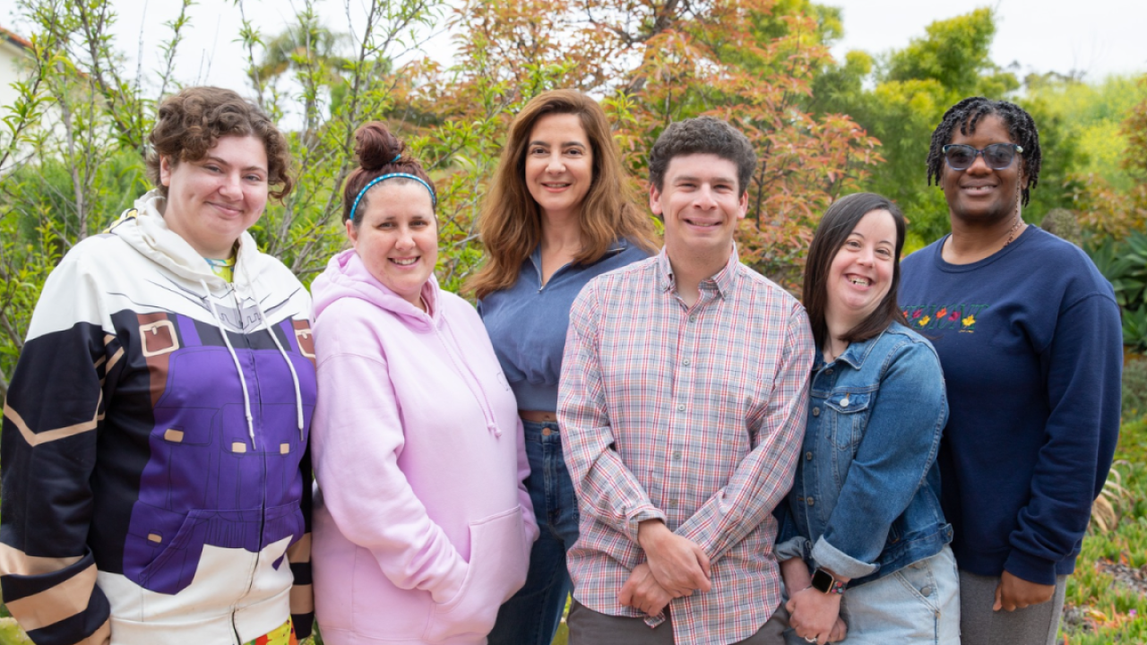 A group of people stood together smiling in front of some outdoor plants