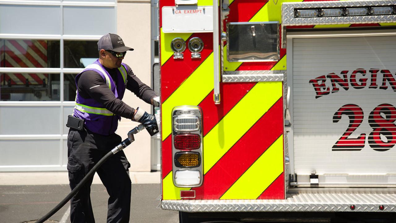 A Booster service professional fuels a fire engine with the number 28 on the back. 
