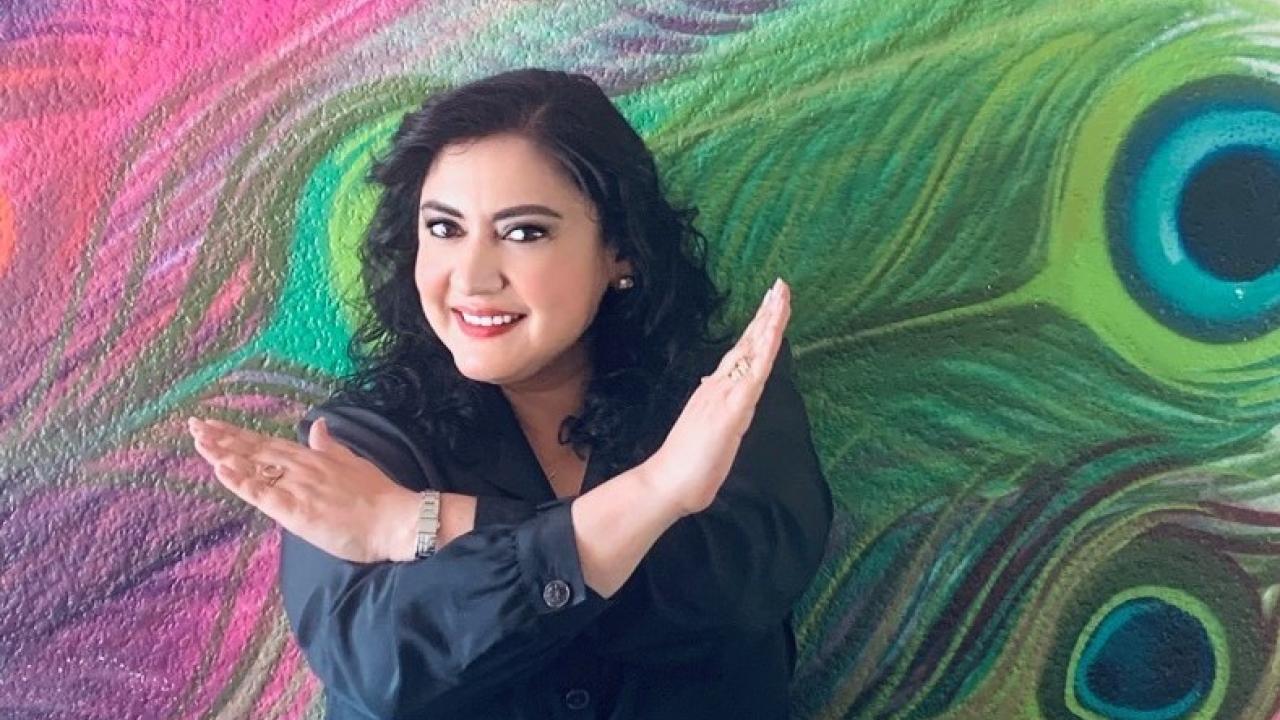 Woman in front of a colorful mural crossing her arms