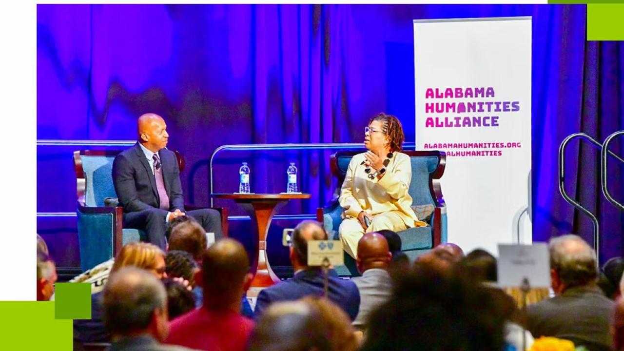 Bryan Stevenson and Michel Martin sit on stage in front of a crowd