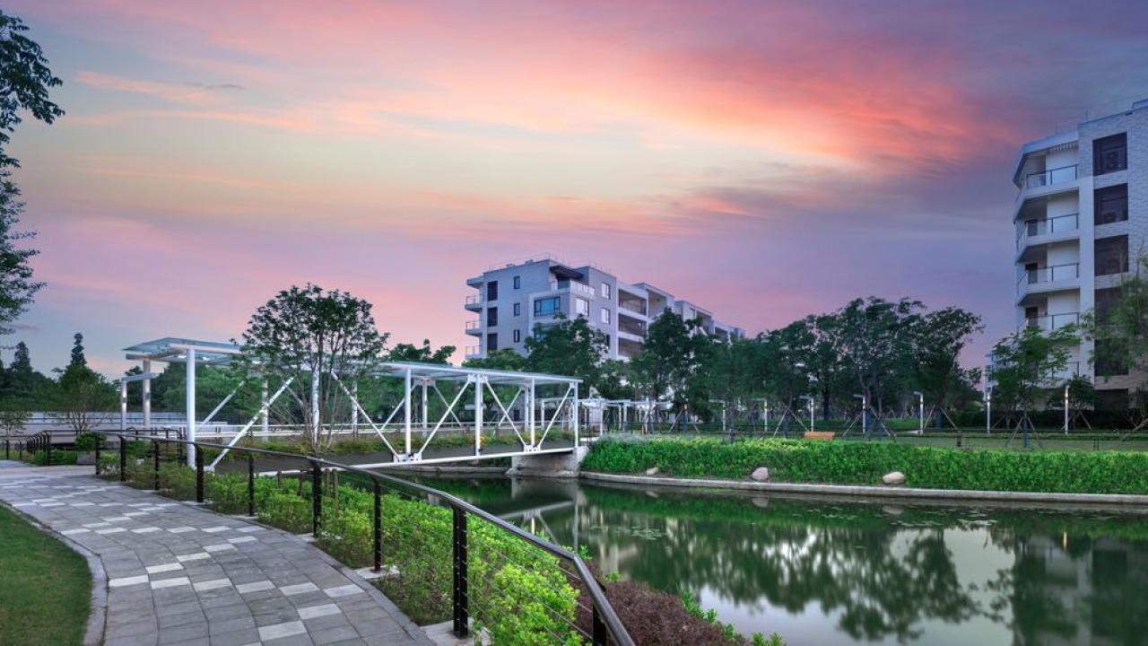 Bridge over water set before apartments at sunset
