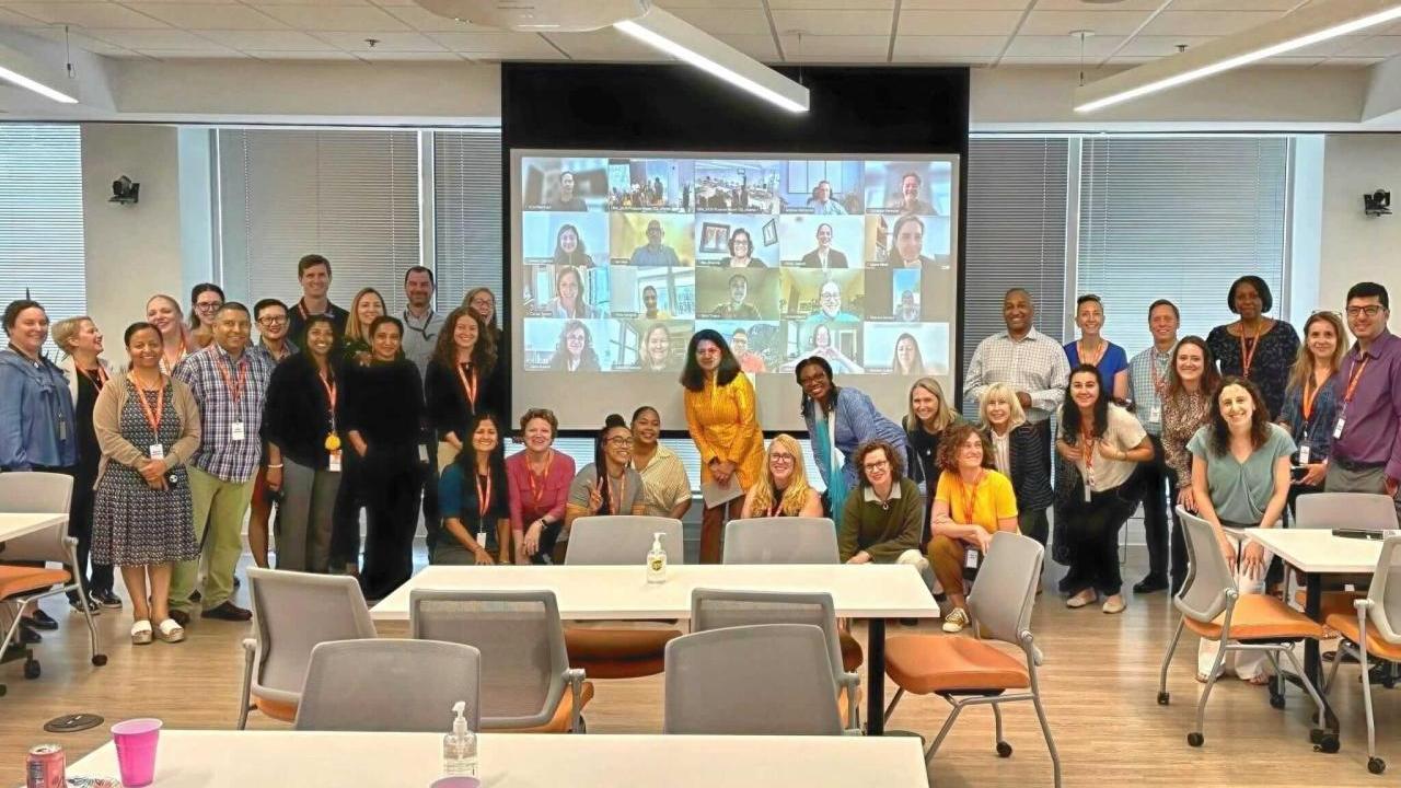 photo of team group standing in front of a screen