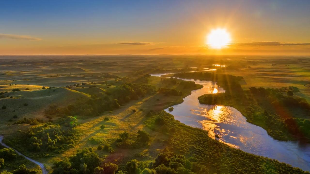 Sunset shown over a river and a valley.
