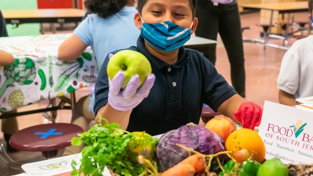 Young boy in a mask holding an apple.