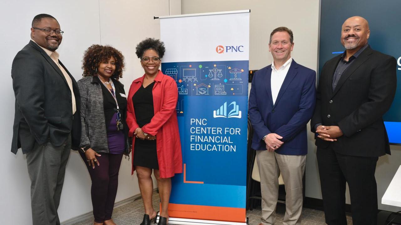 A small group of people stood either side of a PNC Center for Financial Education event banner