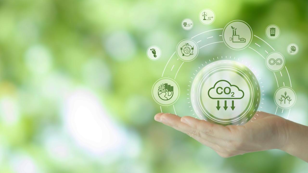 A hand against a green background, with illustrations of CO2 emissions