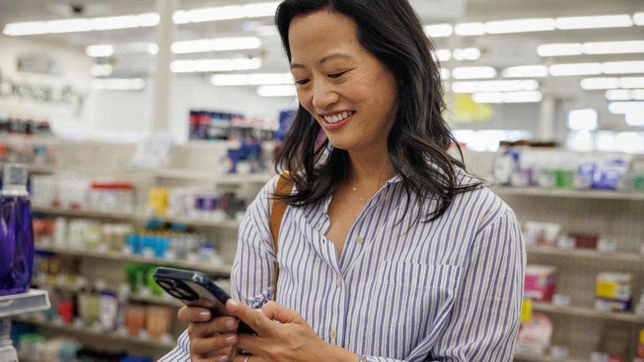A woman in a CVS using an app on her phone.