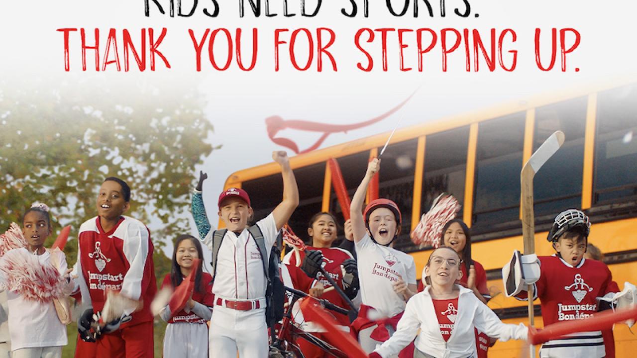 Kids Need sports thank you for stepping up. Kids shown in front of a school bus.