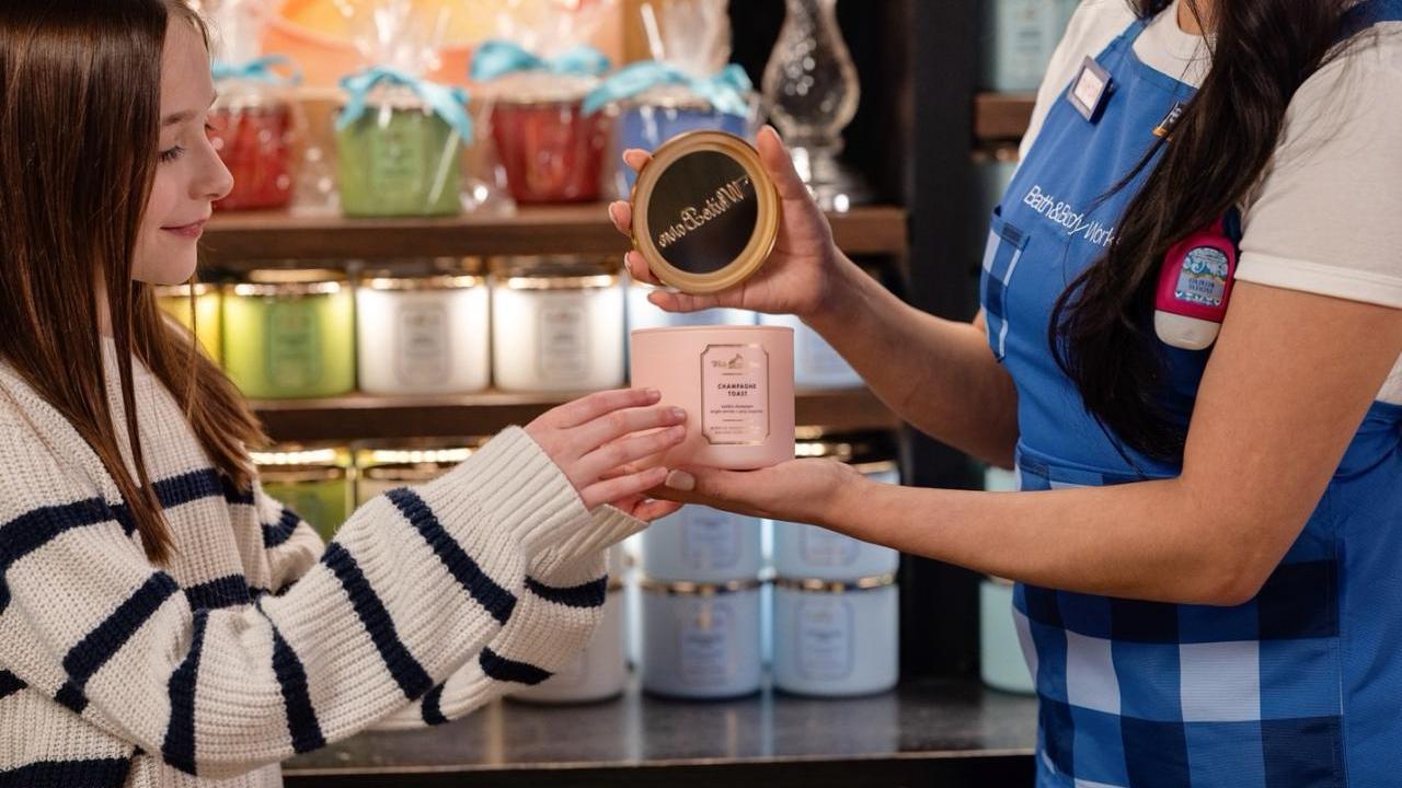 Bath & Body Works employee showing a candle to a customer