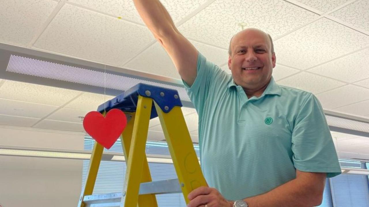 Carl Rohs hanging a red heart from the ceiling.