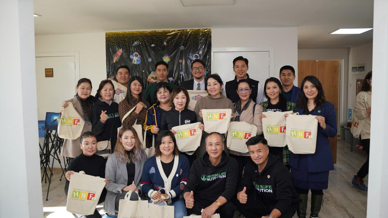 Group of people holding Herbalife Nutrition Foundation tote bags