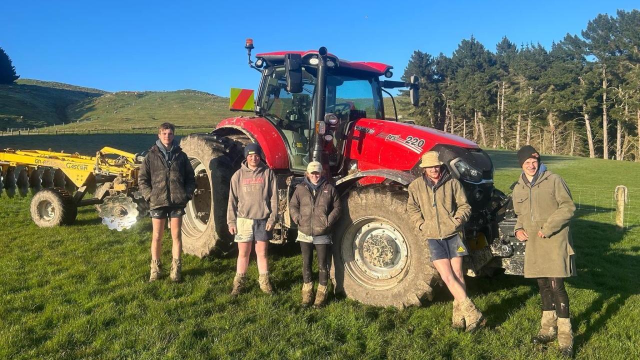 Five people stood in front of a red tractor