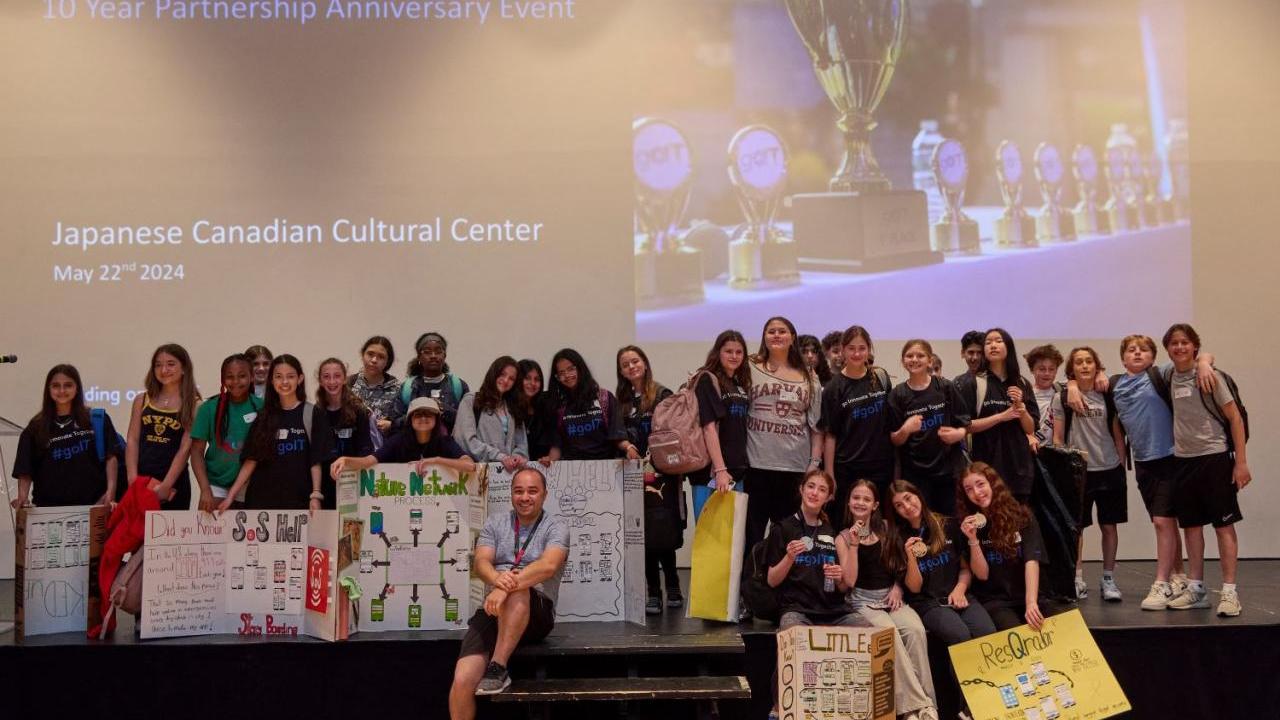 A group of students posed on a stage with project boards.
