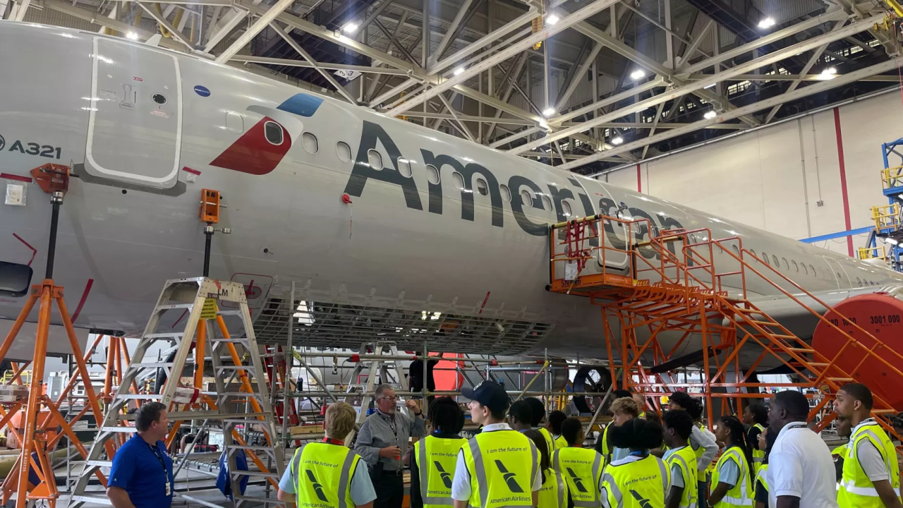 People in high visibility vests standing next to an American Airlines jet inside a hangar