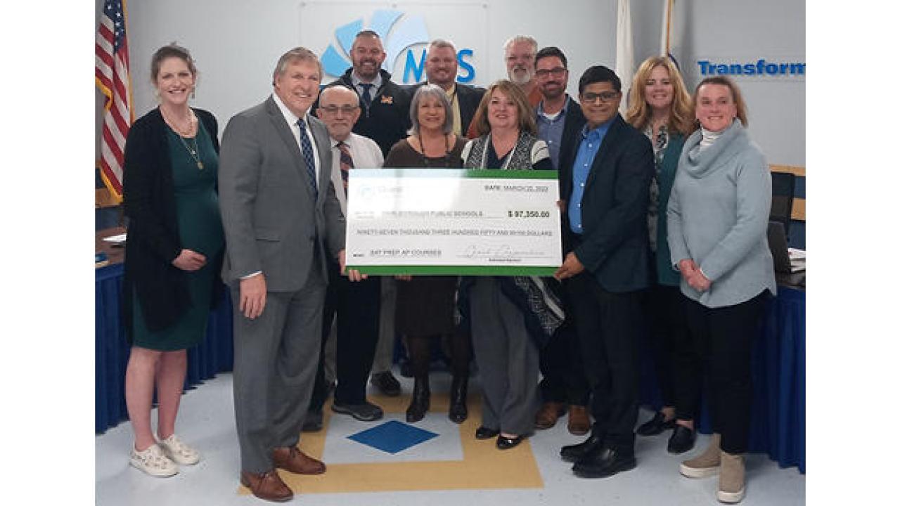 group of people holding up a large check