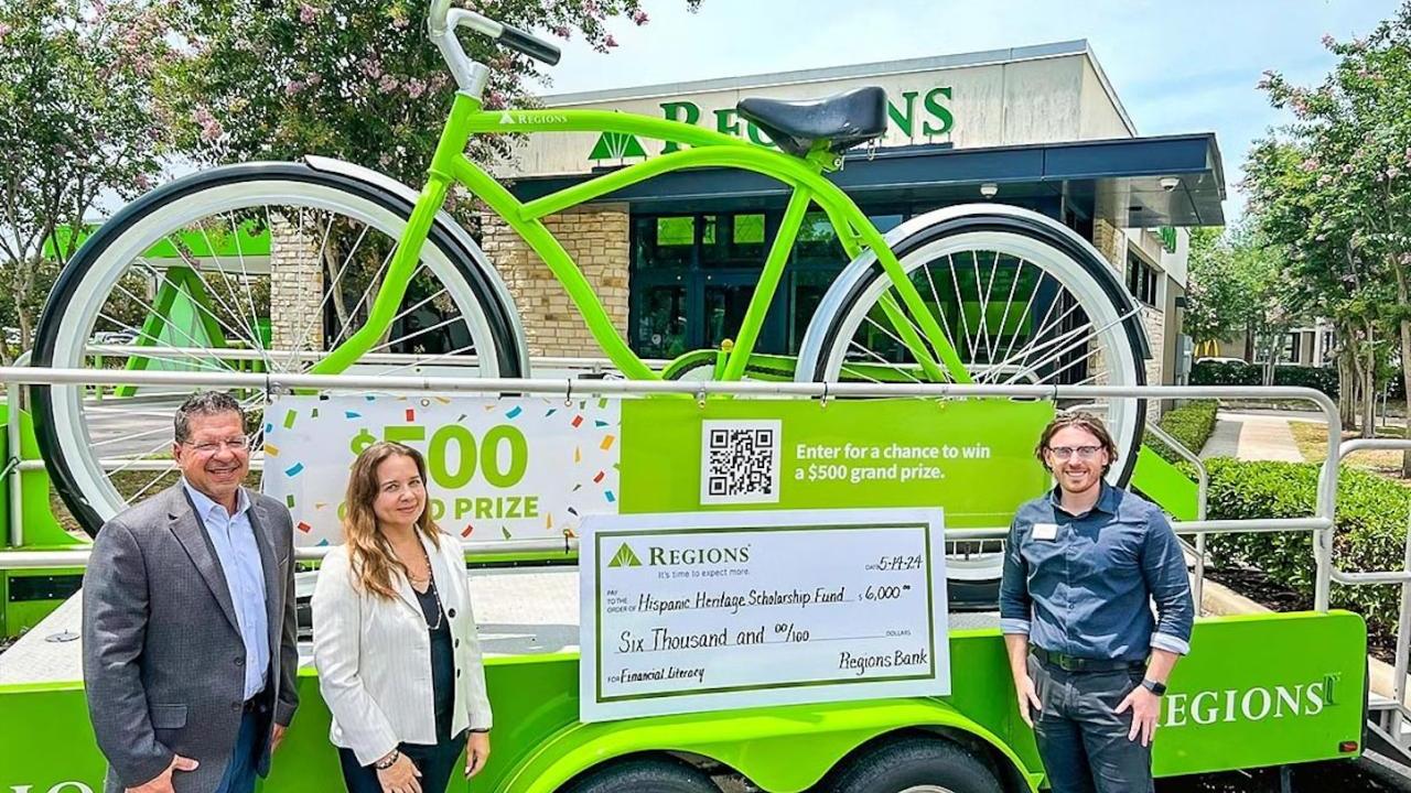 People stood in front of a large green bike on an event float with a cheque on the front 