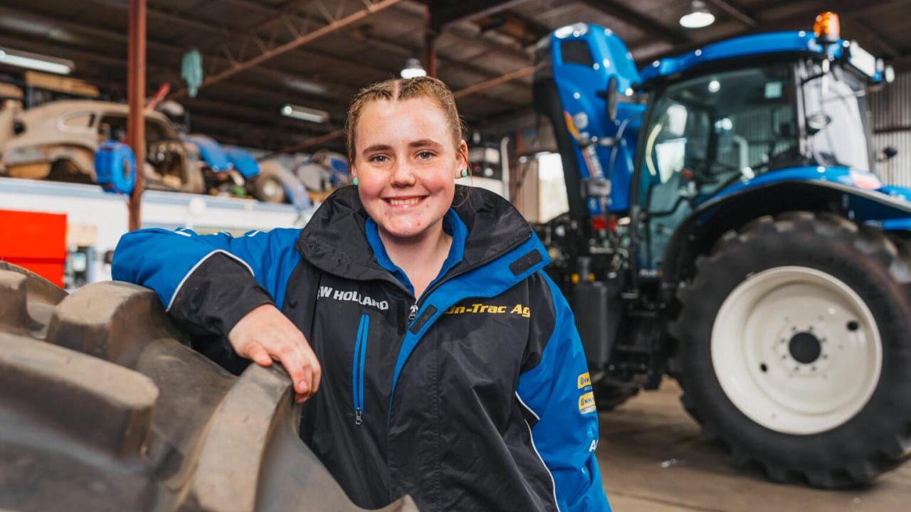 Claire Miller Standing in front of a large tractor.