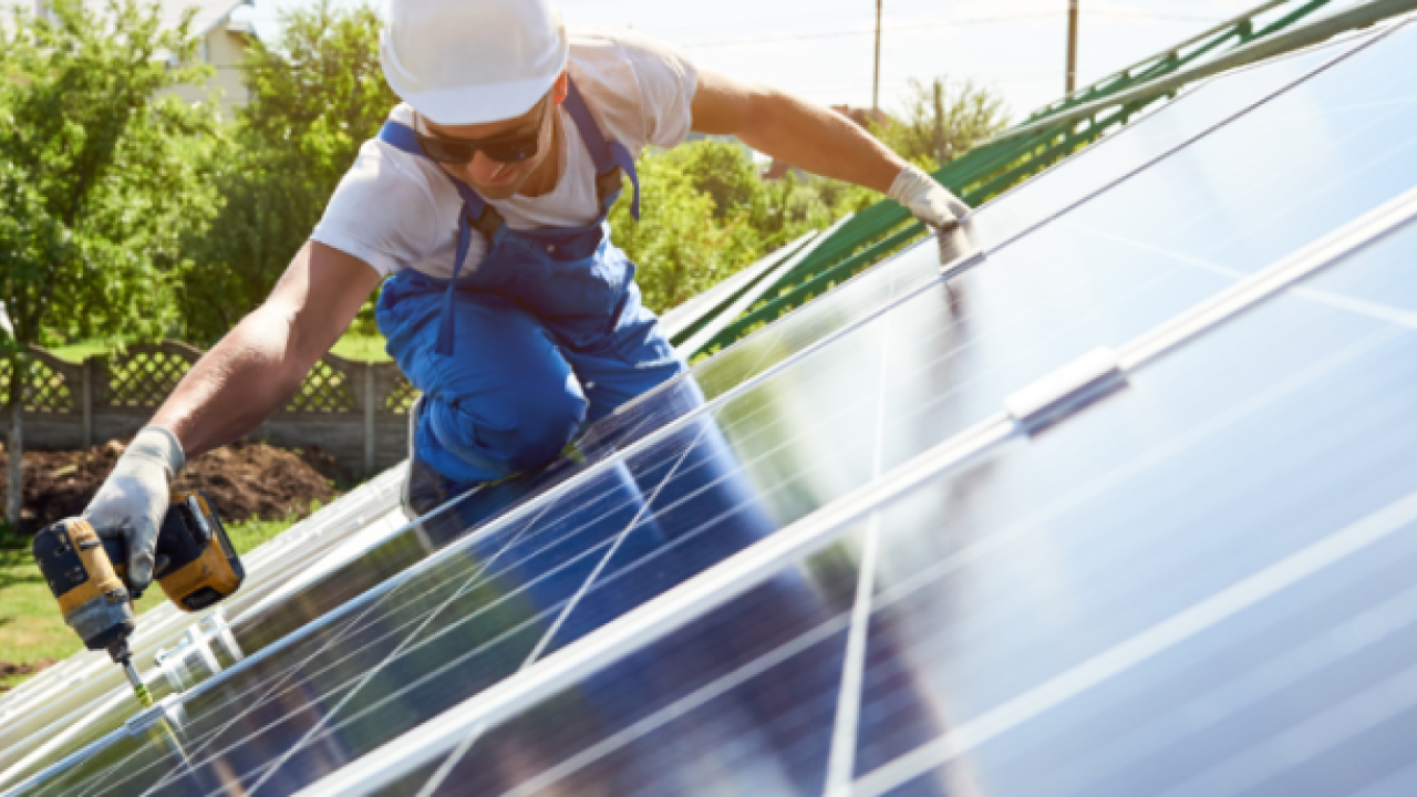 Man with hard hat at work on solar panel