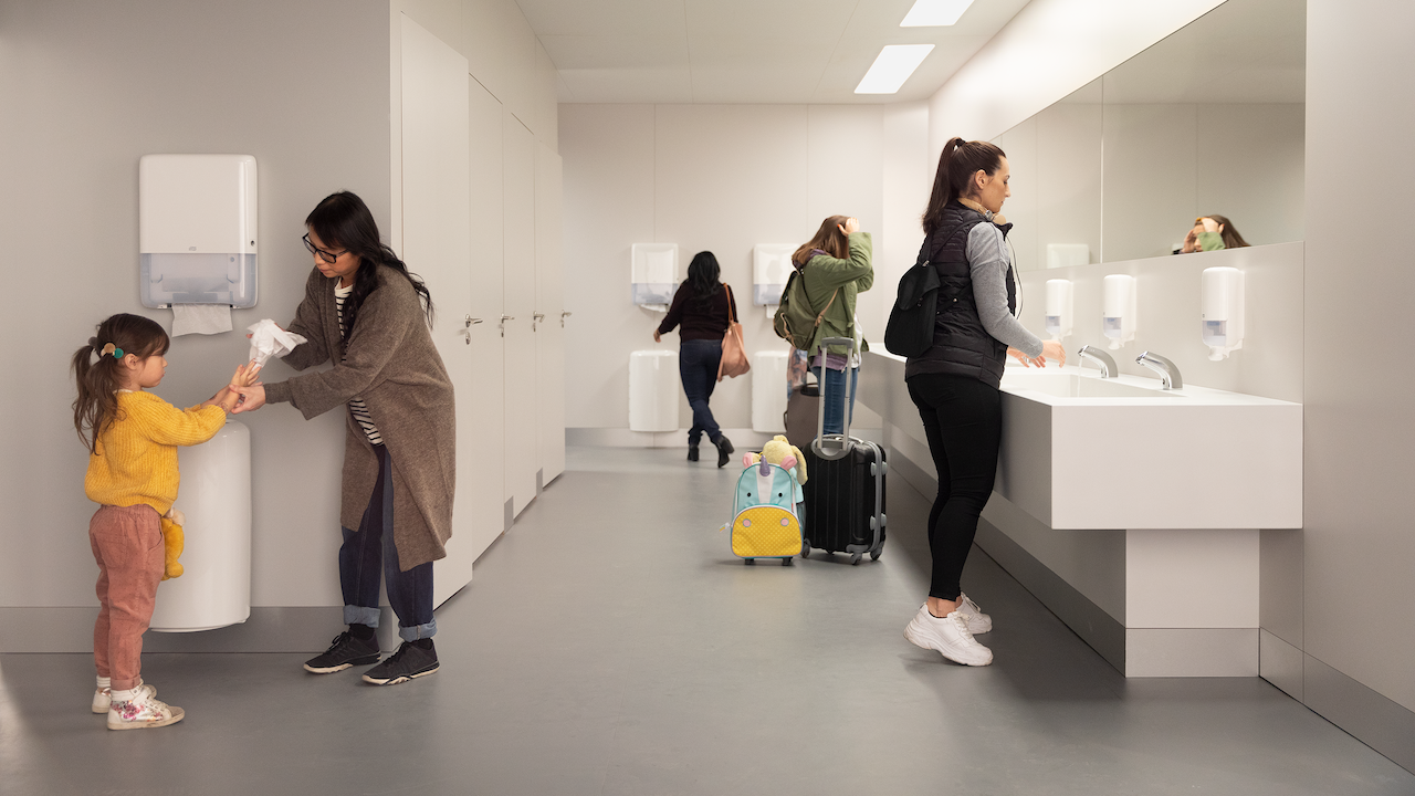 Group of people washing their hands in a restroom. 