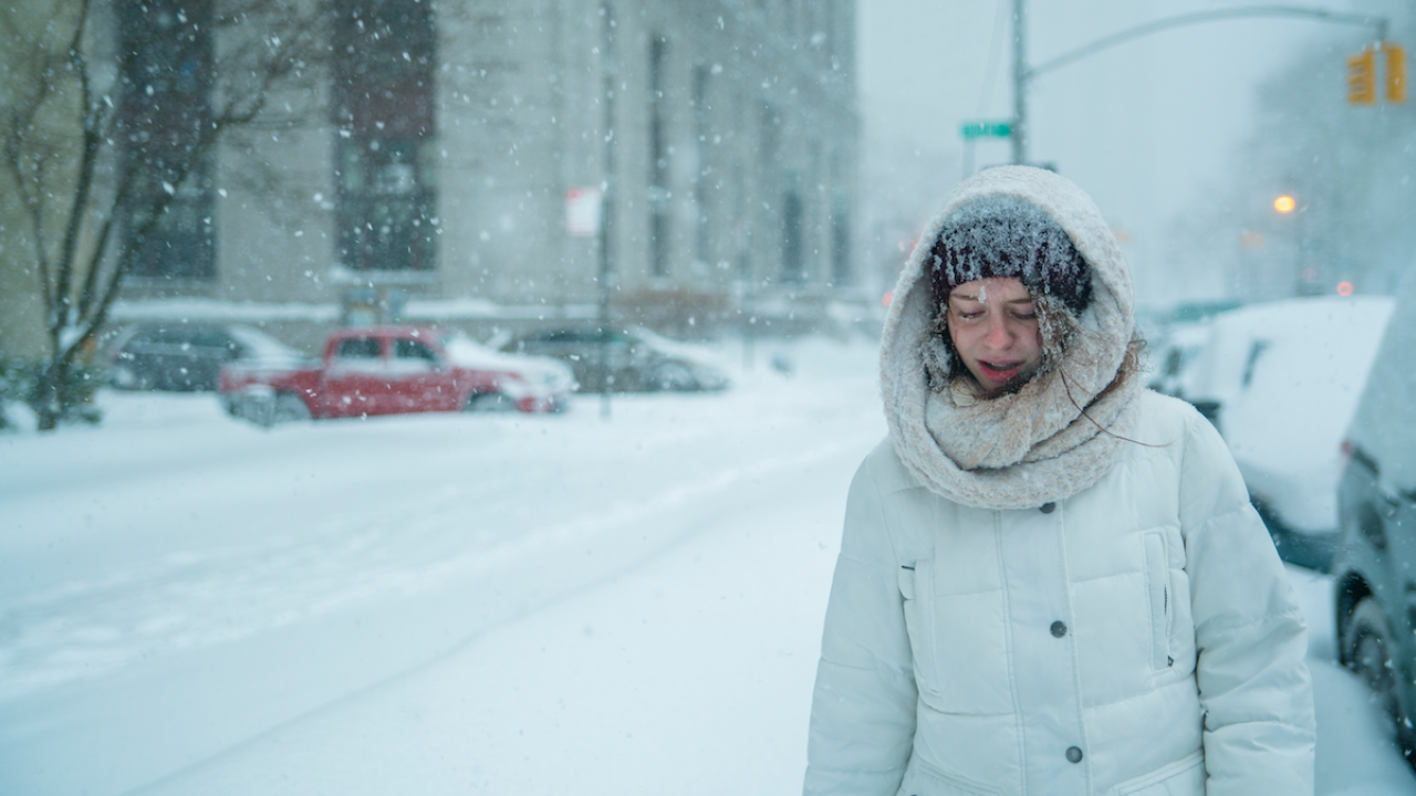 Woman shown in an extreme snow storm in a city.