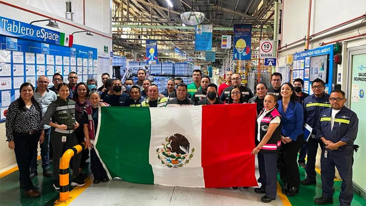 A group of people posed, holding a Mexican flag.