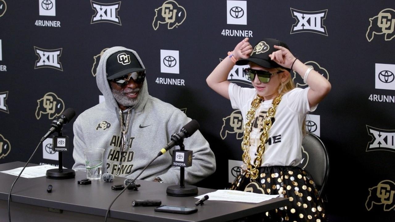 Coach Prime and Piper seated at a table.