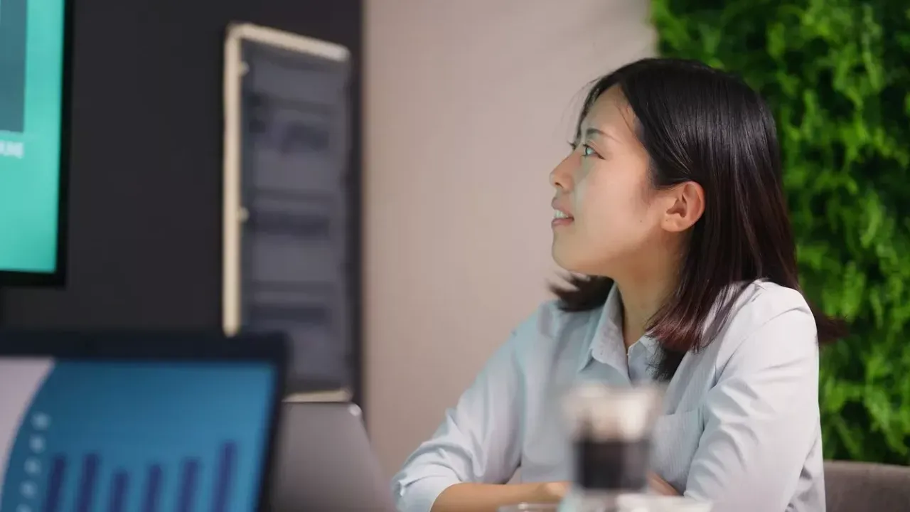 A person sat at a table looking towards a screen on the wall