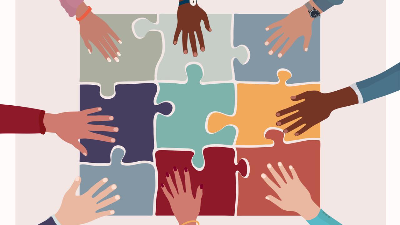 colorful puzzle pieces with hands of many skin colors atop them