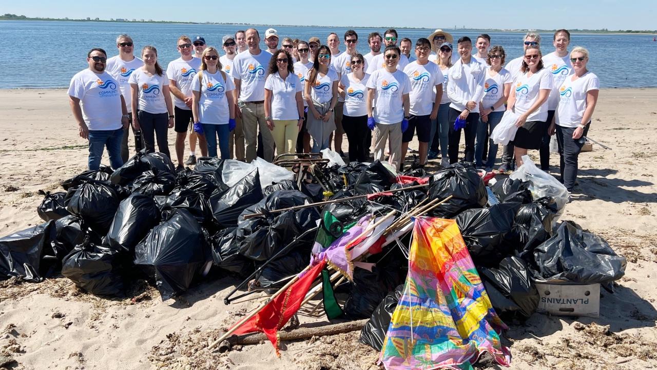 Members of Community Offshore Wind stand on the beach, showing the trash collected during the event