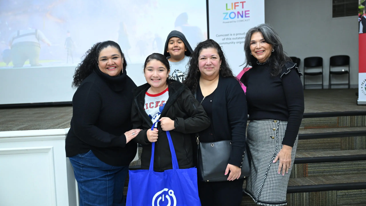 Group photo centering a student who is holding a bag containing the tech tools needed to connect her home to the internet