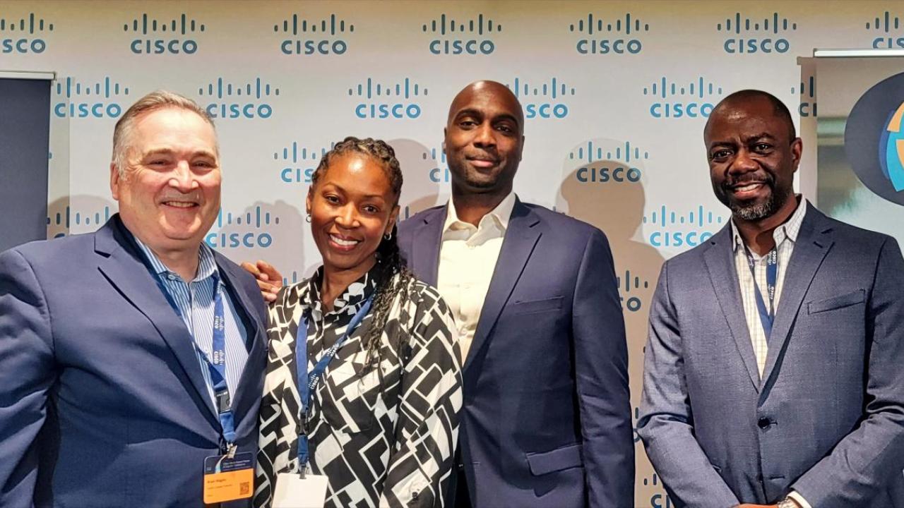 Four people stood in front of a Cisco logo backdrop 