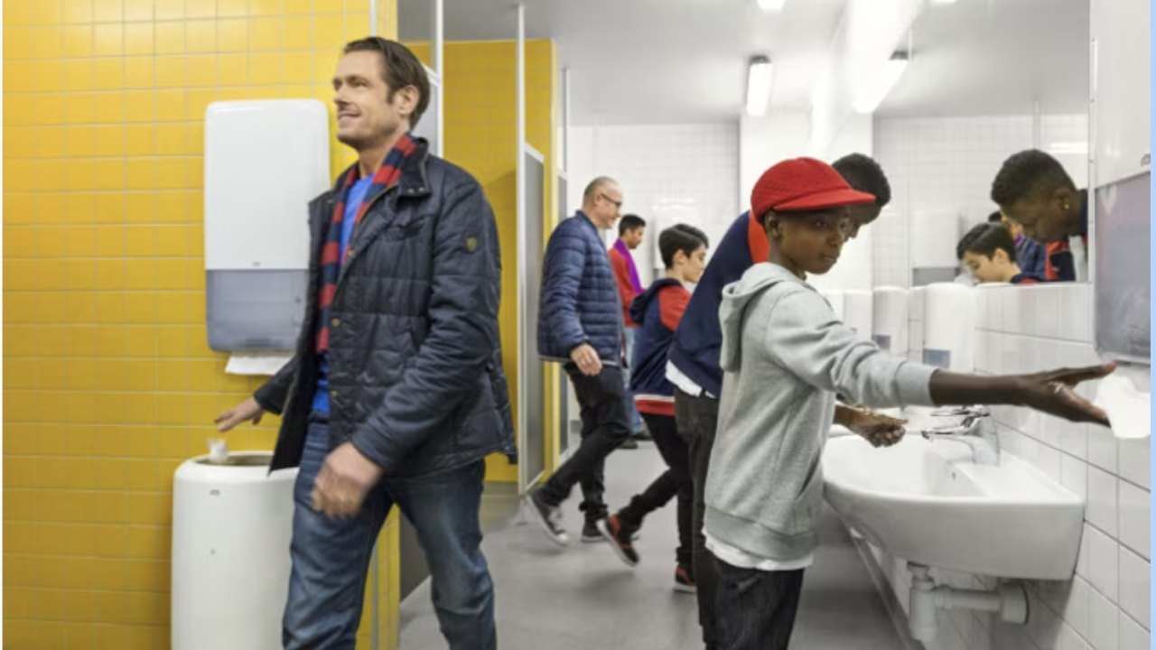 People in a public bathroom using Tork's new hygiene products to wash their hands