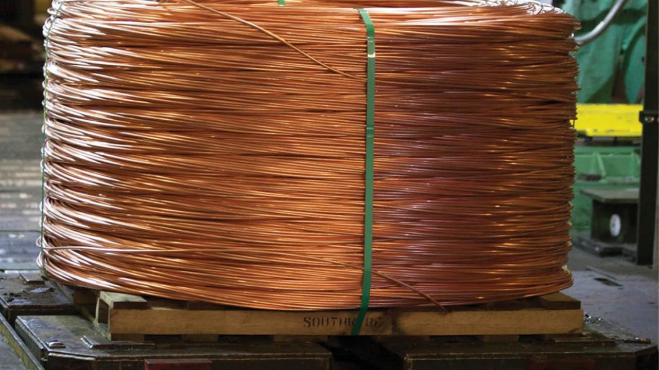 A large bale of coiled copper wire on a pallet in a warehouse.