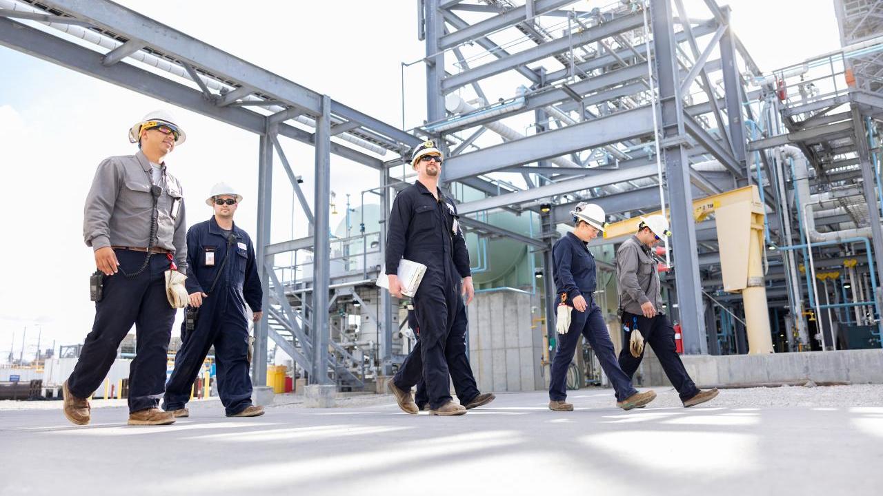 People in hard hats walking in an industrial area.