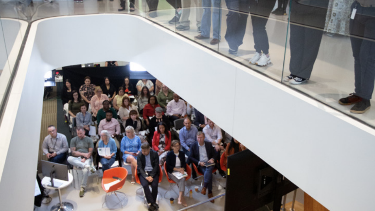 Group of people watching a person give a talk 