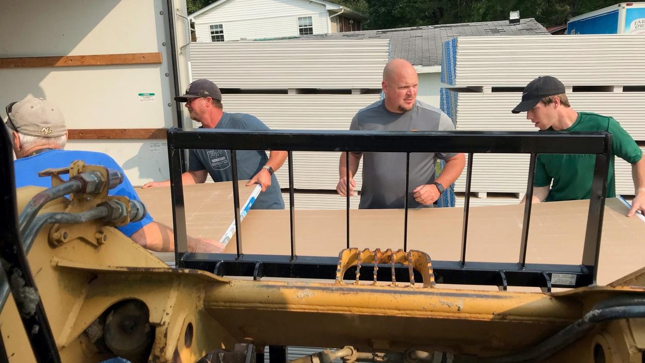 Men unloading wallboard from a truck
