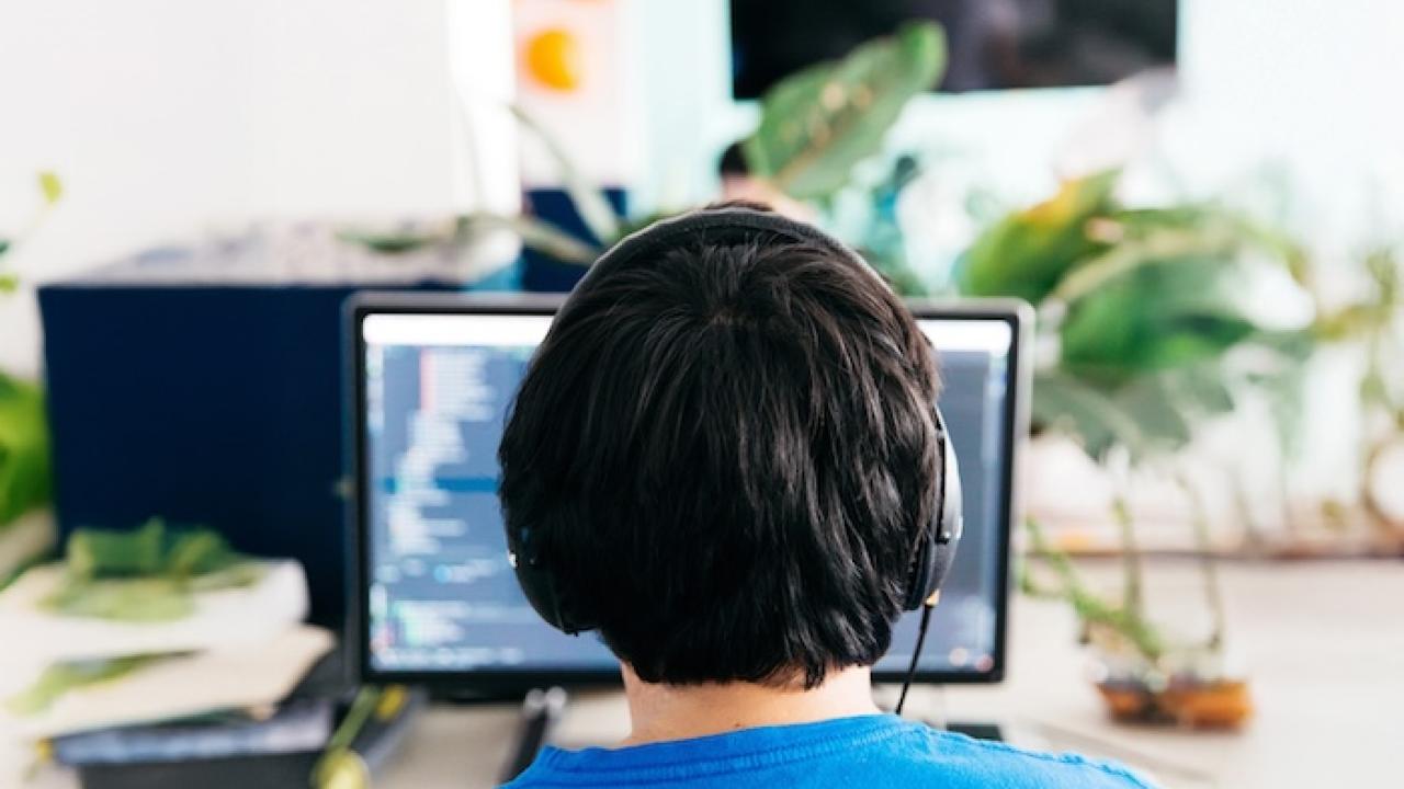 Operator seated behind a desktop computer wearing headphones.