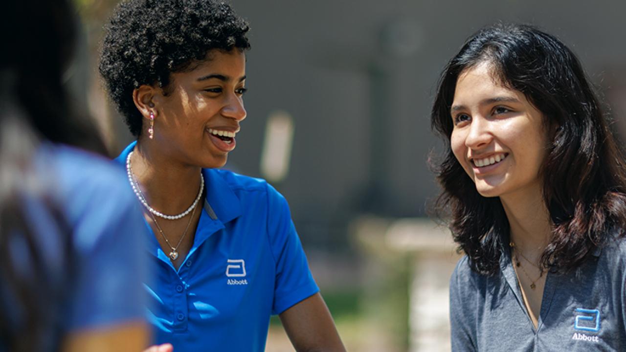 two smiling people wearing shirts with the Abbott logo