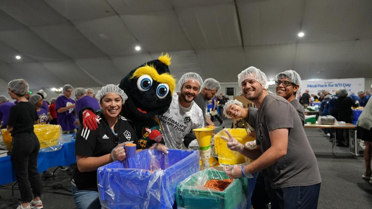 LA Galaxy's mascot Cozmo helps pack meals with volunteers from LA Galaxy.