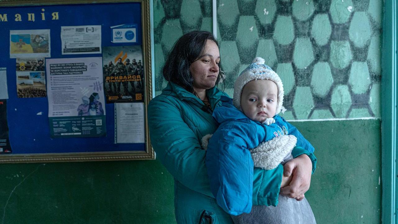 Woman holds baby in clinic with teal walls 