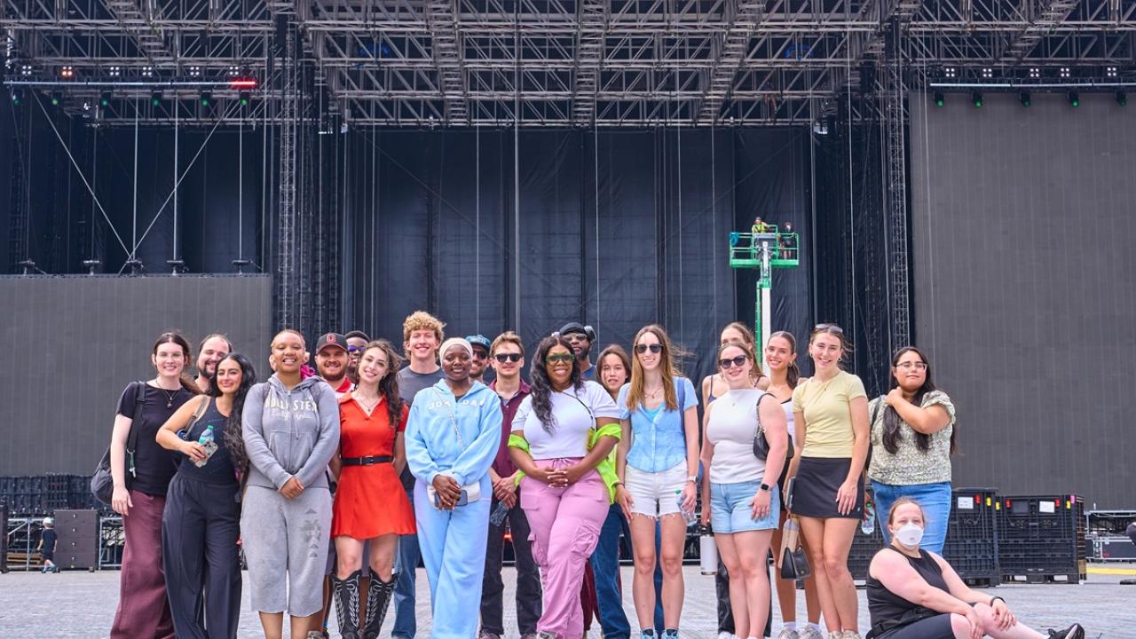 College program participants pose for a group photo in front of the main stage at Buckeye Country Superfest, standing on the festival grounds before the event begins.